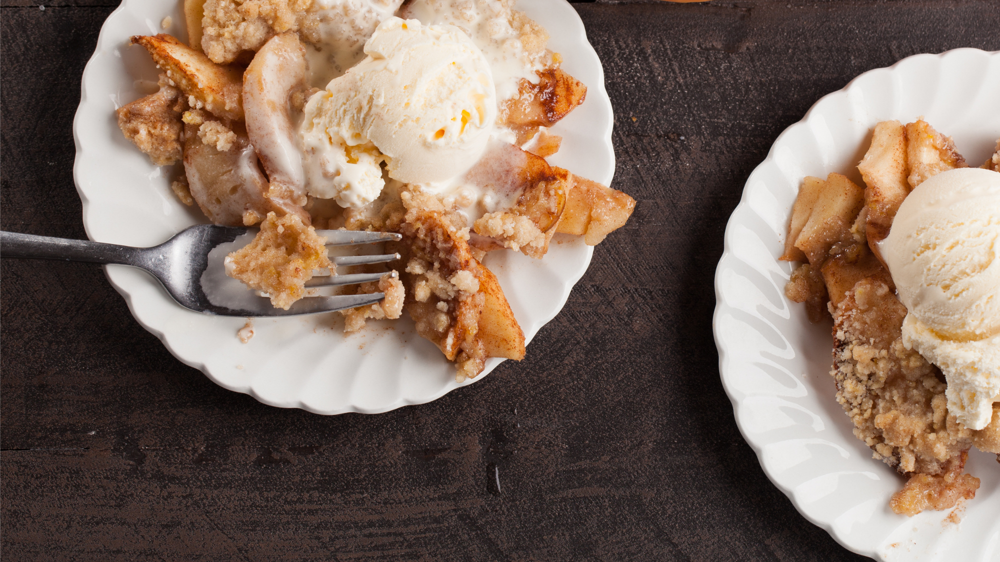 Easy and Delicious Apple Crisp Recipe blog post. A scene of two plates of warm apple crisp with a scoop of vanilla ice cream.