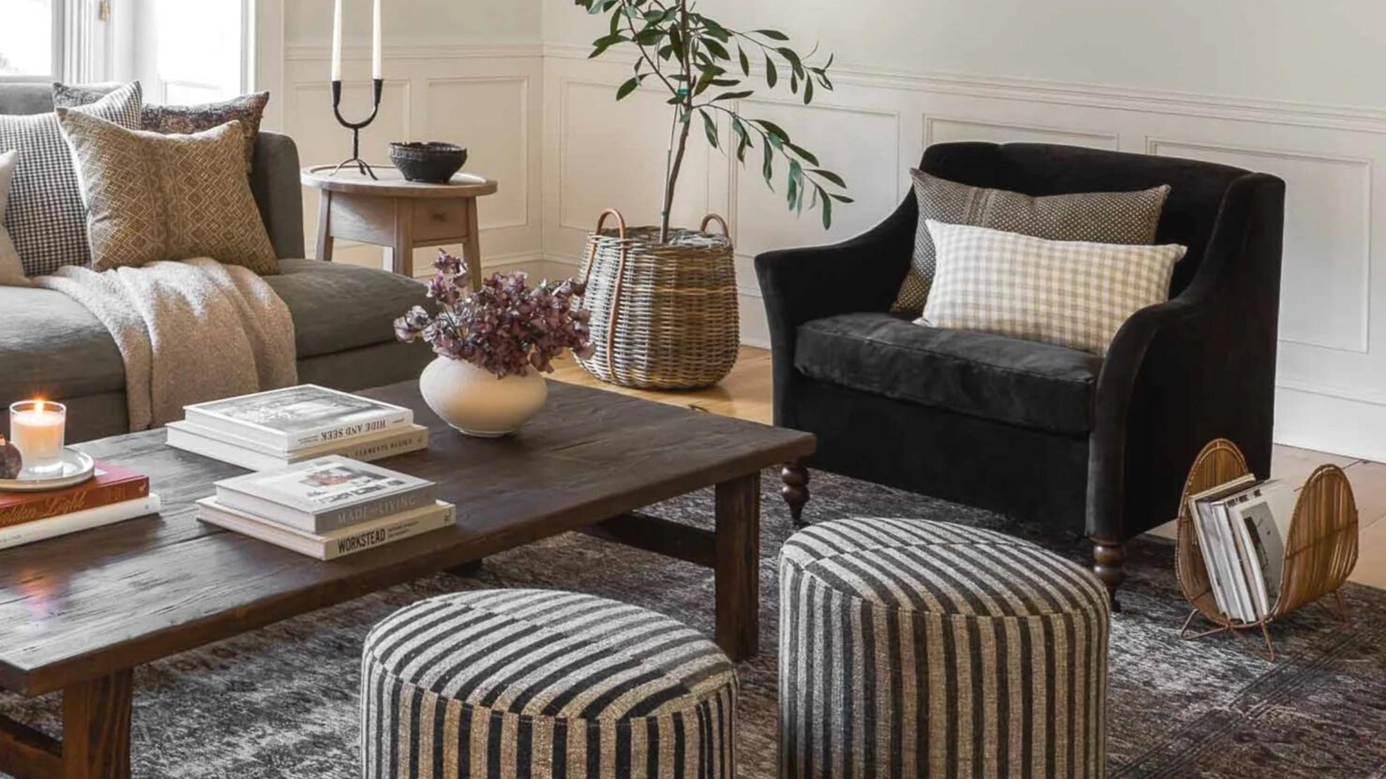 10 Tips to Create a Collected Home blog post. Living room scene with sofa, velvet accent chair, striped ottomans, and styled wooden coffee table with books, vases, and candles.