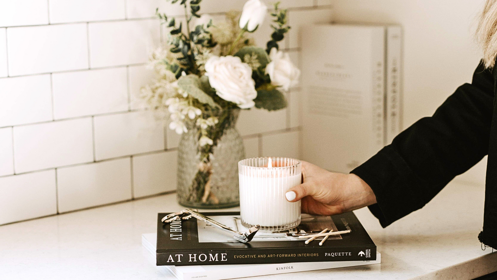 10 Tips to Transition Your Home for Spring blog post. Scene of spring florals in a vase and white jar candle on top of books