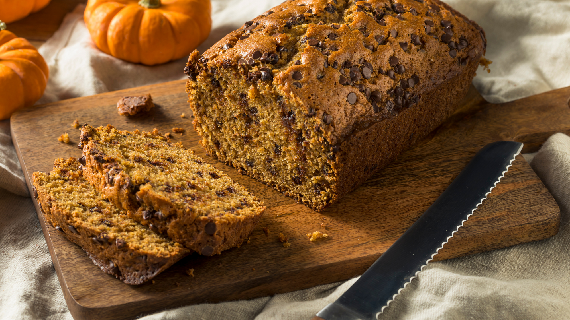 Pumpkin Chocolate Chip Bread Recipe blog post. An image of a loaf of warm pumpkin chocolate chip bread being sliced.